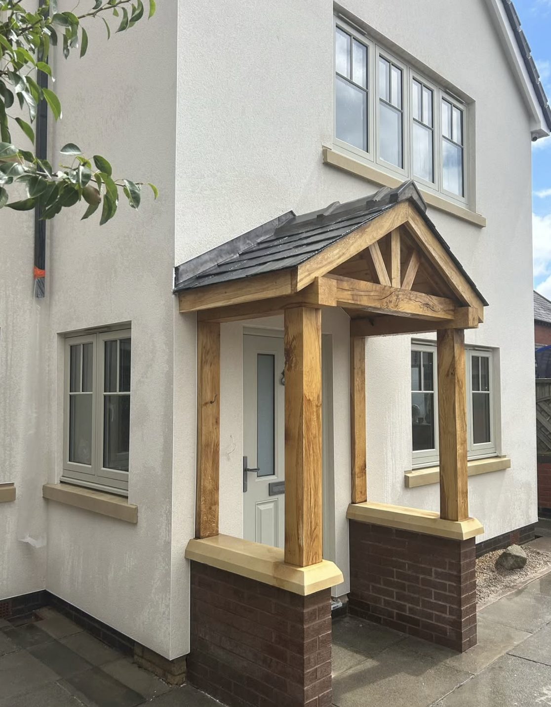 Cream rendered house with an oak framed porch on brick piers