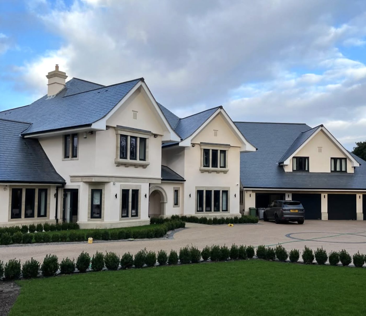 Large detached house in cream render with a long drive