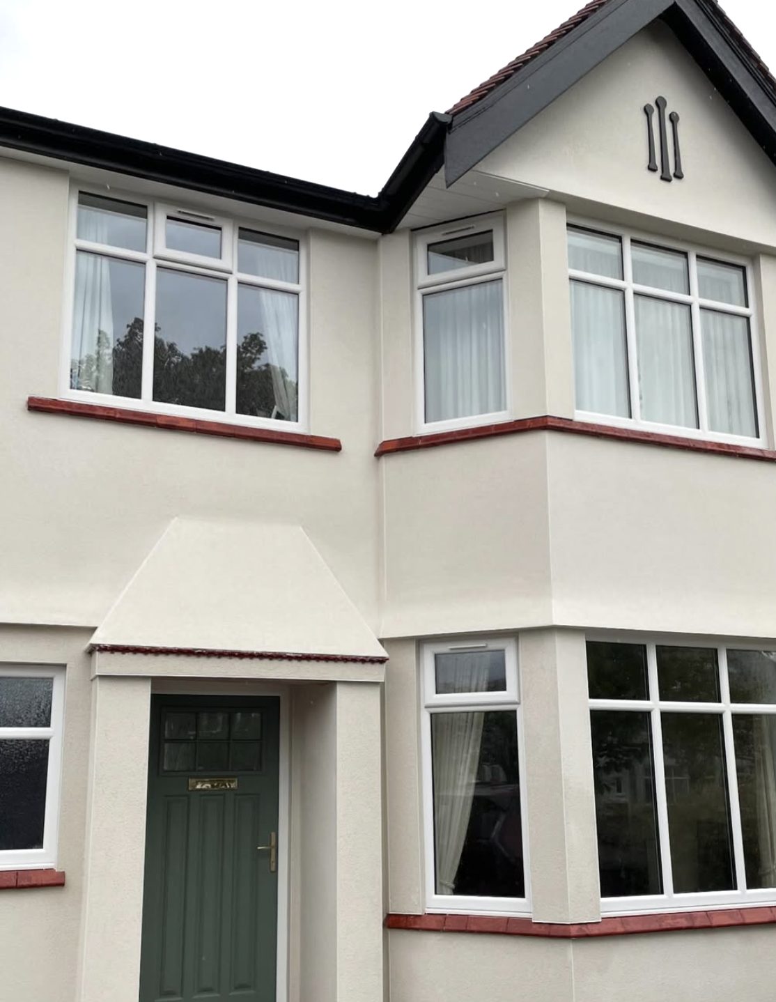 1930s semi-detached house with curved bays in cream render and red tile sills