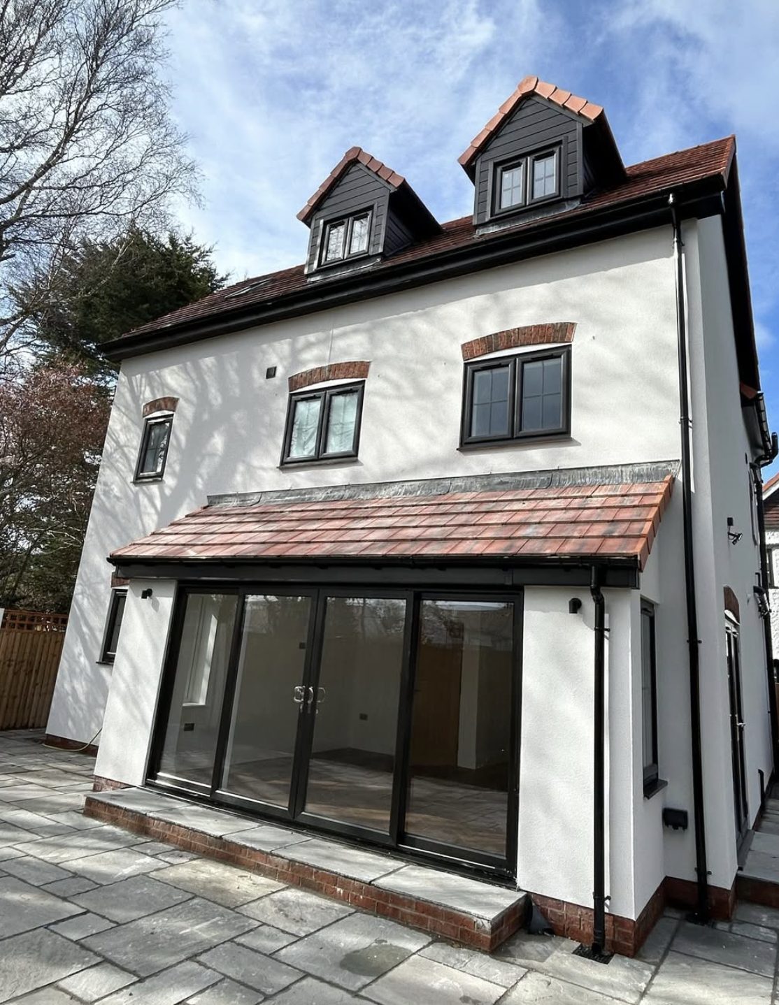 Three-storey back wall in white render with two dormers and a single-storey extension